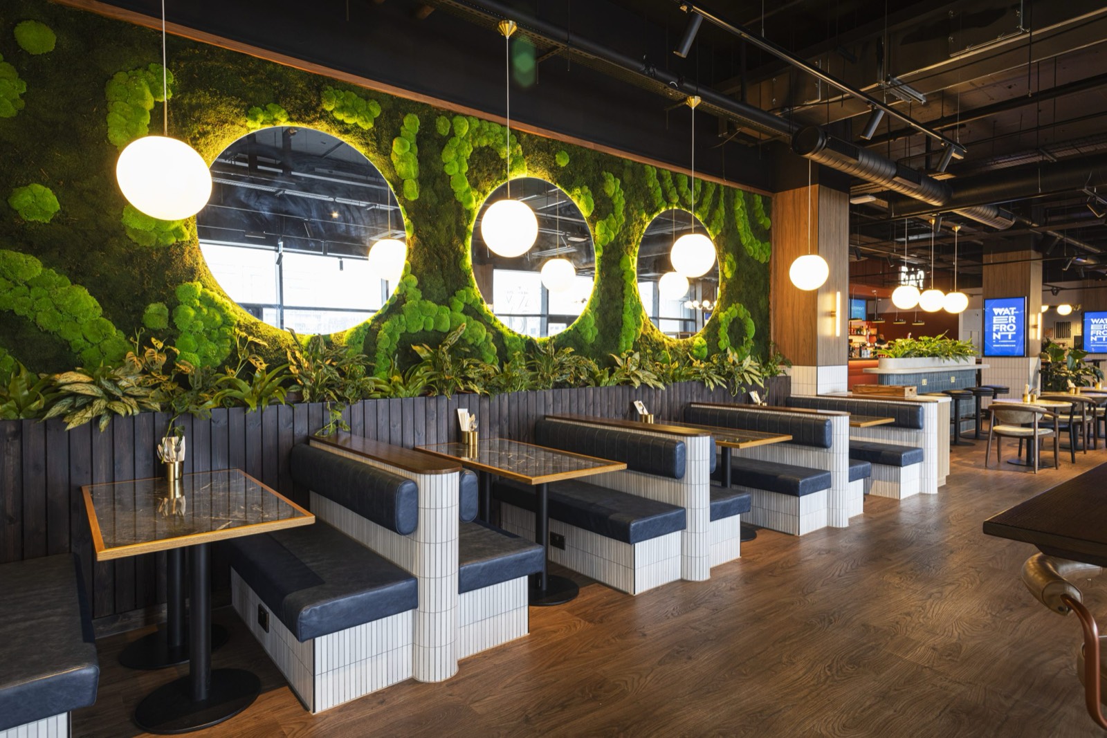 Booth seating beneath a living moss wall